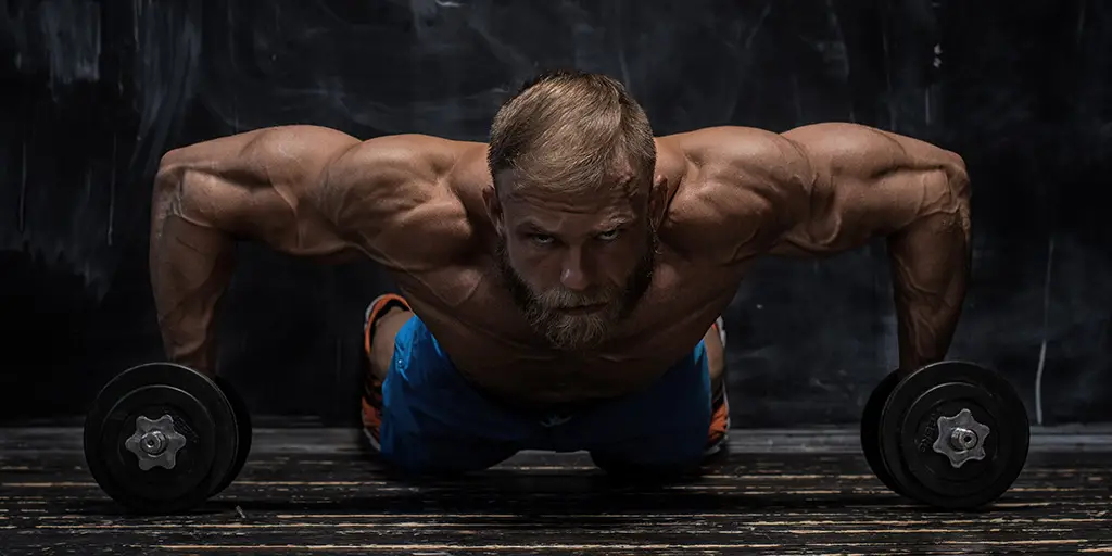 man doing pushups with dumbbells
